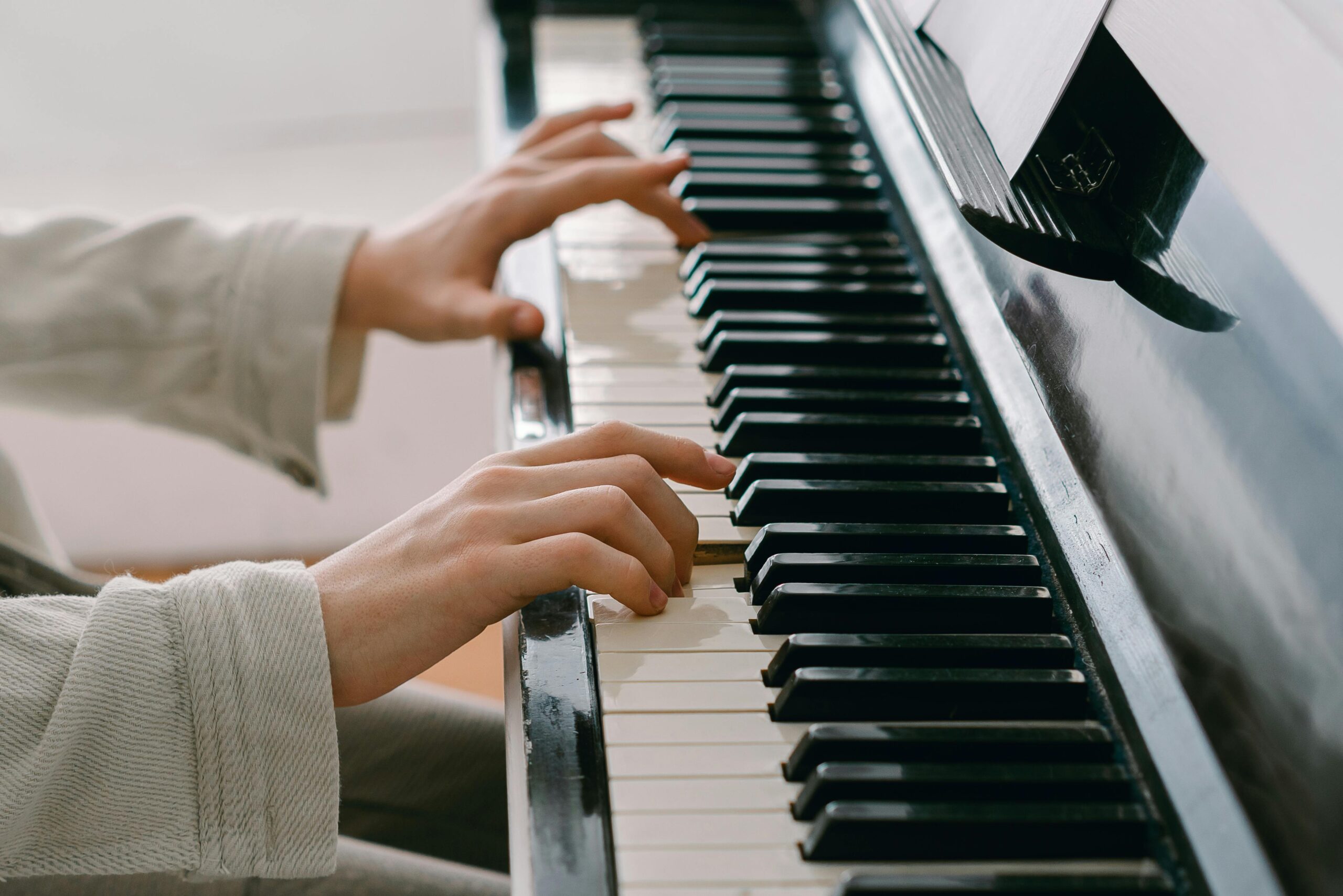 Hands playing piano keys, showcasing musical talent and passion in an indoor setting.