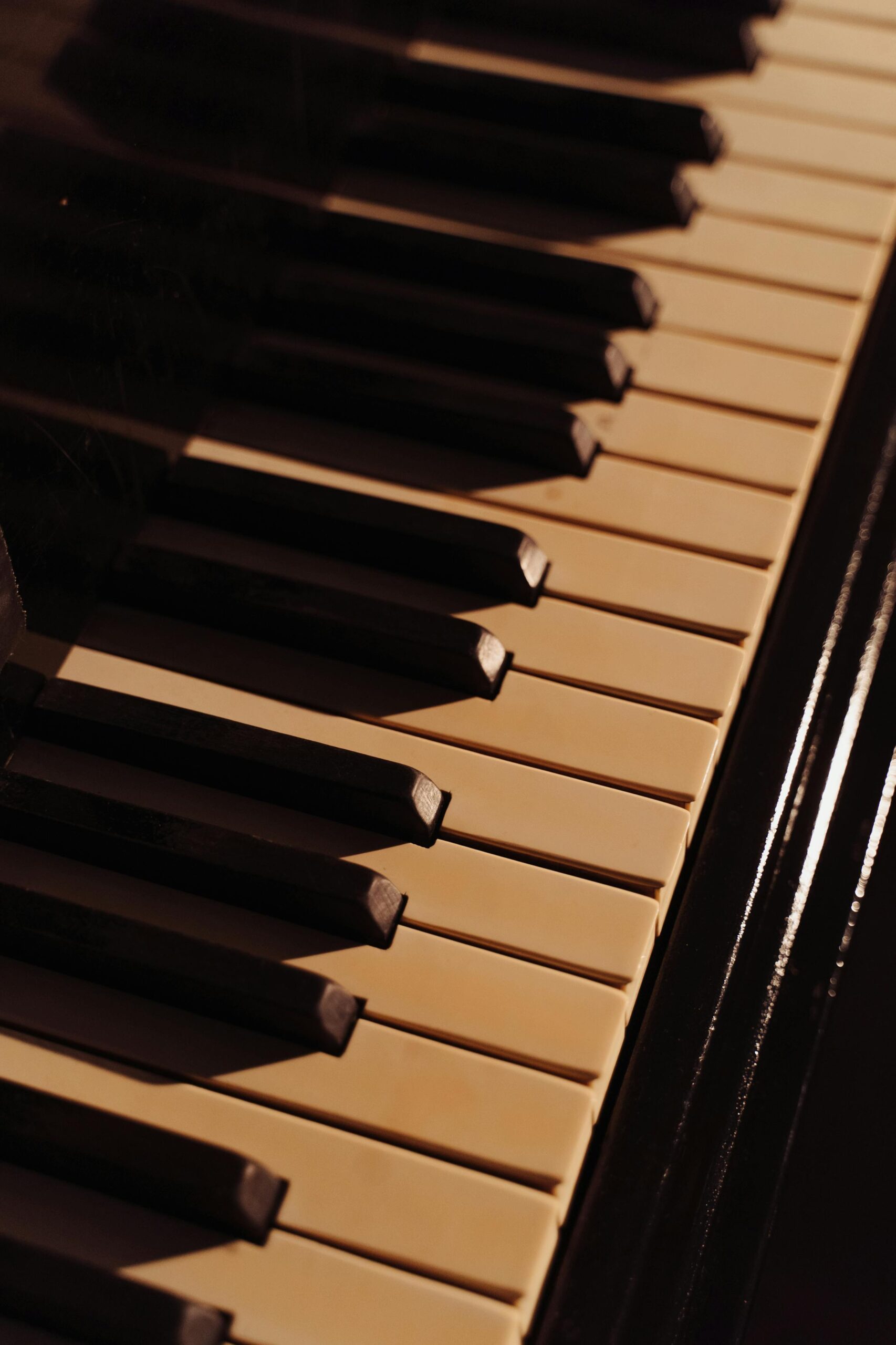 A detailed close-up of piano keys, captured in warm lighting, highlighting the instrument's elegance.
